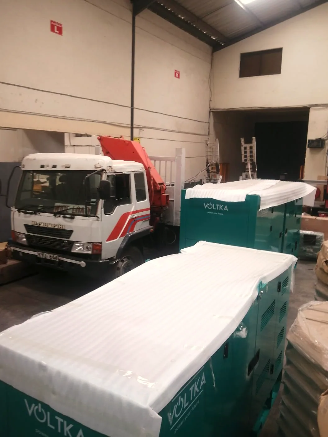 Two VOLTKA generator sets wrapped in the EmersonEIMS Nairobi warehouse beside a crane truck