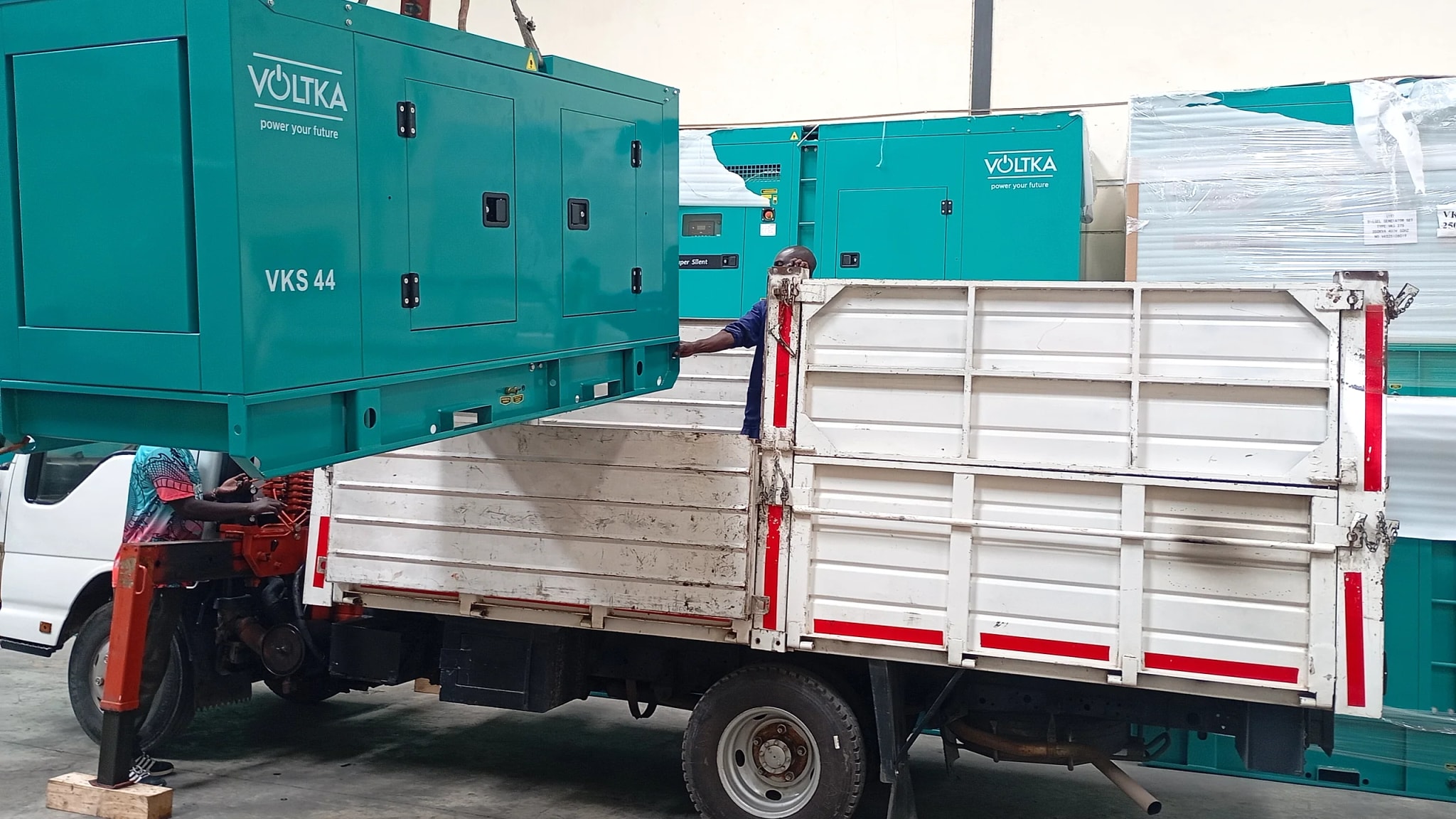 VOLTKA VKS 44 generator lifted by crane above a delivery truck, front angle showing VOLTKA branding